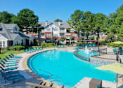 Thumbnail 1 of 22 - A large swimming pool with a waterfall and lounge chairs at Enclave at Wolfchase Apartments, Memphis, 38016