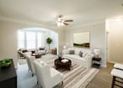 Thumbnail 2 of 32 - A living room with a white couch, a coffee table, and a painting on the wall.