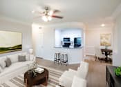 Thumbnail 6 of 32 - A living room with a white couch, a coffee table, and a ceiling fan.