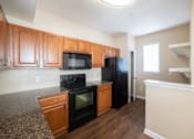 Thumbnail 4 of 16 - A kitchen with black appliances and wooden cabinets.