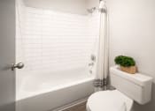Thumbnail 7 of 19 - a white bathroom with a white toilet and a bath tub at 1900 Rosemont, Roswell, Georgia