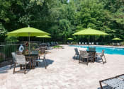 Thumbnail 12 of 19 - a patio with tables and umbrellas next to a swimming pool