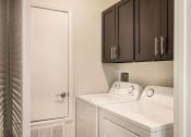 Thumbnail 11 of 30 - a laundry room with white appliances and dark cabinets  at Arlo Luxury homes Apartments, Arkansas
