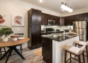 Thumbnail 1 of 30 - spacious kitchen with stainless steel appliances and a breakfast bar with a wooden table and chairs at Arlo Luxury homes Apartments, Little Rock, 72210