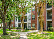 Thumbnail 28 of 30 - a pathway leads through a grassy area in front of an apartment building  at The Aster Sugar Land, Sugar Land