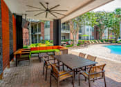 Thumbnail 26 of 30 - a patio with a wooden table and chairs and a pool in the background  at The Aster Sugar Land, Sugar Land