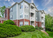 Thumbnail 28 of 31 - A large apartment building with a green lawn in front.