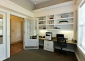 Thumbnail 17 of 31 - A home office with a desk, chair, and shelves.