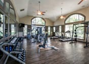 Thumbnail 11 of 31 - A spacious gym with a variety of equipment and a ceiling fan.