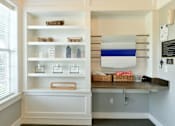 Thumbnail 18 of 31 - A kitchen pantry with white shelves and a blue and white striped towel hanging on the wall.
