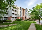 Thumbnail 29 of 31 - A large apartment complex with a well-maintained lawn and trees.