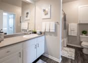 Thumbnail 7 of 31 - A bathroom with a white toilet, sink, and cabinets.