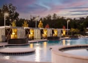 Thumbnail 11 of 14 - a swimming pool at night with a sunset in the background at Esplanade District Apartments, Little Rock, AR,72114