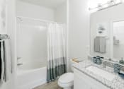Thumbnail 6 of 31 - A white bathroom with a toilet, sink, and shower. at Henley at Mirror Lake, Villa Rica, 30180