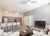 Thumbnail 5 of 21 - A modern living room with a kitchen area in the background.