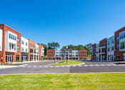 Thumbnail 21 of 21 - A large grassy area in front of a row of buildings.