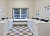 Thumbnail 29 of 34 - a group of washing machines in a room with a window at Legends at Chatham Apartments, Savannah
