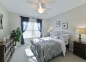 Thumbnail 11 of 34 - a bedroom with a bed and a ceiling fan at Legends at Chatham, Georgia, 31405