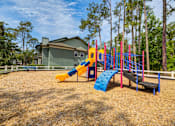 Thumbnail 37 of 58 - A playground with a yellow slide, a blue slide, and a red and blue climbing frame.