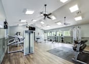 Thumbnail 32 of 58 - A spacious gym with a variety of equipment including a squat rack, bench press, and a television.