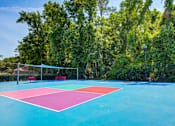 Thumbnail 40 of 58 - A blue and pink tennis court surrounded by trees.