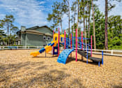Thumbnail 37 of 57 - A playground with a yellow slide, a blue slide, and a red and blue climbing frame.