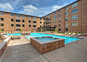 Thumbnail 14 of 15 - A large brick building with a pool in front.