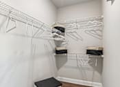 Thumbnail 8 of 43 - A white closet with clothes hanging on hangers.