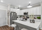 Thumbnail 1 of 43 - A kitchen with white cabinets and a white island.
