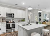 Thumbnail 3 of 43 - A modern kitchen with white cabinets and a large island.
