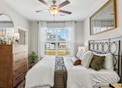 Thumbnail 10 of 43 - A bedroom with a large bed, a ceiling fan, and a view of a balcony through the window.