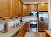Thumbnail 2 of 15 - A kitchen with wooden cabinets and stainless steel appliances.