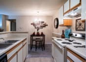 Thumbnail 2 of 29 - a kitchen with white appliances and a dining room with a table at The Summit Apartments, Memphis, Tennessee