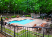 Thumbnail 13 of 29 - a swimming pool with chairs around it and a patio with trees at The Summit Apartments, Memphis, Tennessee