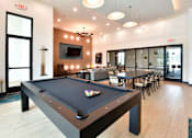 Thumbnail 21 of 29 - A pool table is in the middle of a room with a TV and chairs.