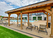 Thumbnail 13 of 29 - A wooden pergola over a pool area with lounge chairs.
