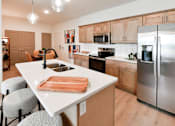 Thumbnail 2 of 29 - A kitchen with a white island and wooden cabinets.