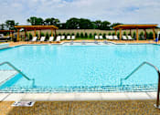 Thumbnail 12 of 29 - A swimming pool with a metal ladder and a poolside with chairs.