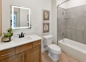 Thumbnail 9 of 29 - A bathroom with a back-lit mirror, bathtub, and toilet
