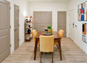 Thumbnail 5 of 29 - A dining room with a table set for four and a bookshelf.