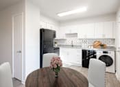 Thumbnail 1 of 19 - a kitchen and dining room with white cabinets and black appliances at Carrolton in Carrolton, GA 30117