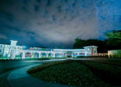 Thumbnail 17 of 22 - the facade of a building at night with lights on it at The Villa at River Pointe, Maumelle, Arkansas