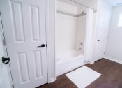 Thumbnail 8 of 22 - a white bathroom with a tub and a white door at The Villa at River Pointe, Arkansas, 72213
