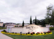 Thumbnail 22 of 22 - the villa entrance sign with flowers and grass at The Villa at River Pointe, Maumelle, Arkansas