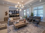 Thumbnail 21 of 26 - A living room with a large couch, a coffee table, and a chandelier. at Hall Creek Apartment Homes, Arlington