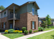 Thumbnail 24 of 26 - A brick building with a balcony and a small garden in front. at Hall Creek Apartment Homes, Arlington, TN, 38002