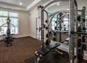 Thumbnail 16 of 26 - A gym with a squat rack, bench, and weights. at Hall Creek Apartment Homes, Arlington