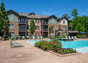 Thumbnail 12 of 26 - A large apartment complex with a pool and lounge chairs. at Hall Creek Apartment Homes, Arlington 38002