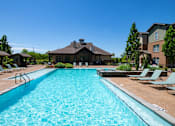 Thumbnail 13 of 26 - A large swimming pool in front of a house with a brown roof. at Hall Creek Apartment Homes, Arlington, Tennessee