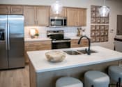 Thumbnail 3 of 28 - A kitchen with a refrigerator, microwave, oven, sink, and bar stools. at Grays Creek Apartments, Tennessee, 38018